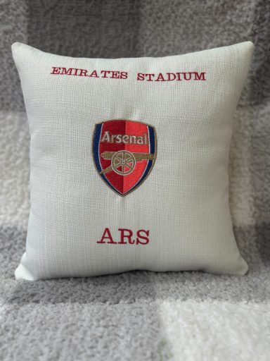 A cushion featuring the Arsenal FC logo and "Emirates Stadium" text.