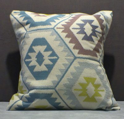 Decorative pillow with a geometric pattern in blue, green, and brown hues.